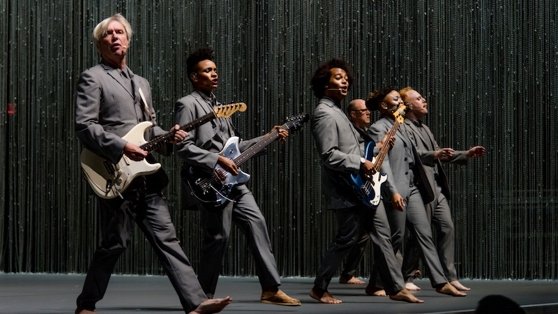 David Byrne and his group playing and singing on stage